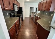 Thumbnail 16 of 39 - a kitchen with brown cabinets and a wood floor
