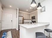 Thumbnail 21 of 32 - A kitchen with a white countertop and a blue rug on the floor.