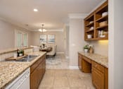 Thumbnail 10 of 50 - A kitchen with granite countertops and wooden cabinets.