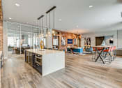 Thumbnail 3 of 30 - A modern kitchen with a wooden floor and a brick wall.