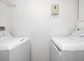Thumbnail 10 of 36 - Two white washing machines in a laundry room.