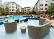 Thumbnail 34 of 41 - a large swimming pool with chairs around it in front of an apartment building
