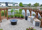 Thumbnail 38 of 41 - a patio with a fire pit and a lake with buildings in the background