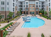 Thumbnail 33 of 41 - an outdoor pool with lounge chairs and an apartment building