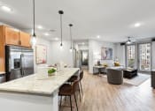Thumbnail 24 of 41 - an open kitchen and living room with a marble counter top