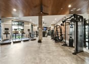Thumbnail 15 of 41 - a gym with cardio equipment and a ceiling fan