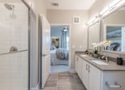Thumbnail 12 of 37 - A bathroom with a walk-in shower, double sink vanity, and a large mirror.