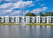 Thumbnail 53 of 78 - a fountain in the middle of a lake with an apartment building in the background at Altis Blue Lake, Lake Worth, Florida