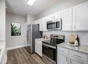 Thumbnail 3 of 37 - A kitchen with white cabinets and a wooden floor.