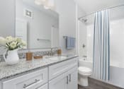 Thumbnail 21 of 49 - A white bathroom with a white toilet, a sink, a mirror, and a shower.