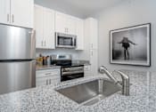 Thumbnail 9 of 49 - A modern kitchen with granite countertops and stainless steel appliances.