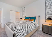 Thumbnail 8 of 14 - A bedroom with a bed covered in a black and white patterned bedspread.