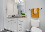 Thumbnail 22 of 49 - A bathroom with a white toilet and a yellow towel.