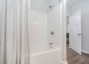Thumbnail 7 of 14 - A white bathroom with a shower and a door.