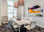 Thumbnail 16 of 18 - A conference room with a white table and chairs, a large abstract painting on the wall, and a floor lamp.