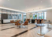 Thumbnail 17 of 18 - A modern dining area with wooden floors and a mix of round and square tables.
