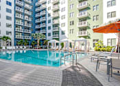 Thumbnail 5 of 18 - North Miami Beach, FL, Luxury Apartments Near North Beach - Lazul - Swimming Pool Surrounded By Lounge Chairs, Umbrellas, Cabanas, Trees, And A View Of The Apartments.