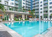 Thumbnail 2 of 18 - A large swimming pool in front of a building with a balcony.