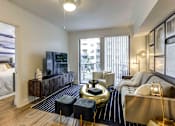 Thumbnail 9 of 18 - North Miami Beach, FL, Luxury Apartments Near Sunny Isles Beach - Lazul - Living Room With Porcelain Wood Plank Flooring, Couch, Armchair, Media Console, Tv, Ottomans, Gold Coffee Table, And Lamps.