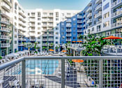 Thumbnail 4 of 18 - North Miami Beach, FL Luxury Apartments Near North Beach - Lazul - Elevated Sundeck with Umbrella Tables, Chairs, and View of Pool with Poolside Lounge Seats and Cabanas.