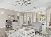 Thumbnail 16 of 29 - A living room with a white ceiling fan and grey couches.