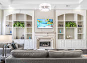 Thumbnail 14 of 18 - A living room with a grey couch and a fireplace.