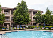 Thumbnail 18 of 18 - A swimming pool in front of a building surrounded by trees.
