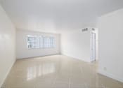 Thumbnail 10 of 22 - A spacious room with a window and a white door.
