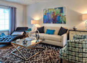 Thumbnail 8 of 35 - A living room with a couch, a chair, a coffee table, and a painting on the wall.