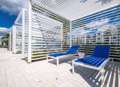 Thumbnail 46 of 78 - a patio with two blue lounge chairs and a white railing at Altis Blue Lake, Lake Worth, 33467