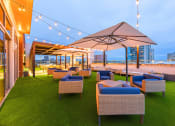 Thumbnail 36 of 47 - Two-Bedroom Luxury Apartments In Atlanta, GA - Venue Brookwood - Rooftop Terrace With City Skyline Views, Turf Grass, Lounge Seating, Umbrellas, Pavilion, And Cafe Lights.