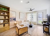 Thumbnail 5 of 38 - Apartments in Panama City Beach, FL, with In-Unit Washer and Dryer - Vintage Lake Powell - Living Room With Built-In Wood Shelving, White Sofa, Coffee Table, Ceiling Fan, And Large Windows.