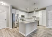 Thumbnail 26 of 31 - A modern kitchen with a white island and stainless steel appliances.