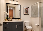 Thumbnail 22 of 40 - A bathroom with a white toilet and a sink with a mirror above it.