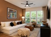 Thumbnail 21 of 40 - A living room with a white couch and a painting on the wall.