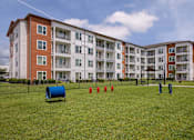 Thumbnail 20 of 27 - A large apartment complex with a green lawn in front.