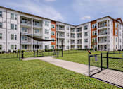 Thumbnail 19 of 27 - Apartment complex with a green lawn in front.