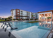Thumbnail 16 of 27 - A large swimming pool in front of a building with a sun lounger.
