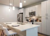 Thumbnail 3 of 27 - A kitchen with a white countertop and white chairs.
