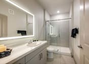 Thumbnail 9 of 27 - A bathroom with a sink, mirror, and shower.