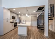 Thumbnail 4 of 27 - A modern kitchen with a white island and wooden floors.