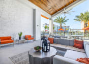Thumbnail 13 of 23 - 2-Bedroom Apartments in Daytona Beach, FL - Madison Pointe - Clubhouse Patio with a Sectional Sofa, Coffee Table, Armchairs, Outdoor Tables and Chairs, Ceiling Fan, and View of Pool.