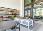 Thumbnail 12 of 23 - Two Bedroom Apartments in Daytona Beach, FL - Madison Pointe - Community Clubhouse with Table, Chairs, Couch, and Glass Walls