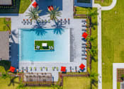 Thumbnail 11 of 23 - Apartments in Daytona Beach, FL for Rent - Madison Pointe - Aerial View of Resort-Style Pool with Island, Palm Trees, Spacious Sun Deck, Lounge Chairs, Umbrellas, Pavilion, and Pergola.