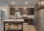Thumbnail 27 of 49 - A kitchen with a stainless steel refrigerator and a white countertop.