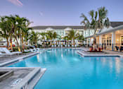 Thumbnail 3 of 49 - A large swimming pool surrounded by palm trees and lounge chairs.