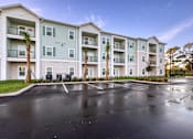 Thumbnail 47 of 49 - A large apartment complex with a parking lot in front.