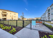 Thumbnail 43 of 49 - A fenced area with a sign and a bench in front of apartment buildings.