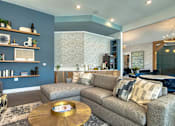Thumbnail 10 of 49 - A living room with a grey couch and a wooden coffee table.