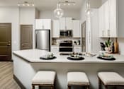 Thumbnail 20 of 34 - A modern kitchen with a large island and stools.